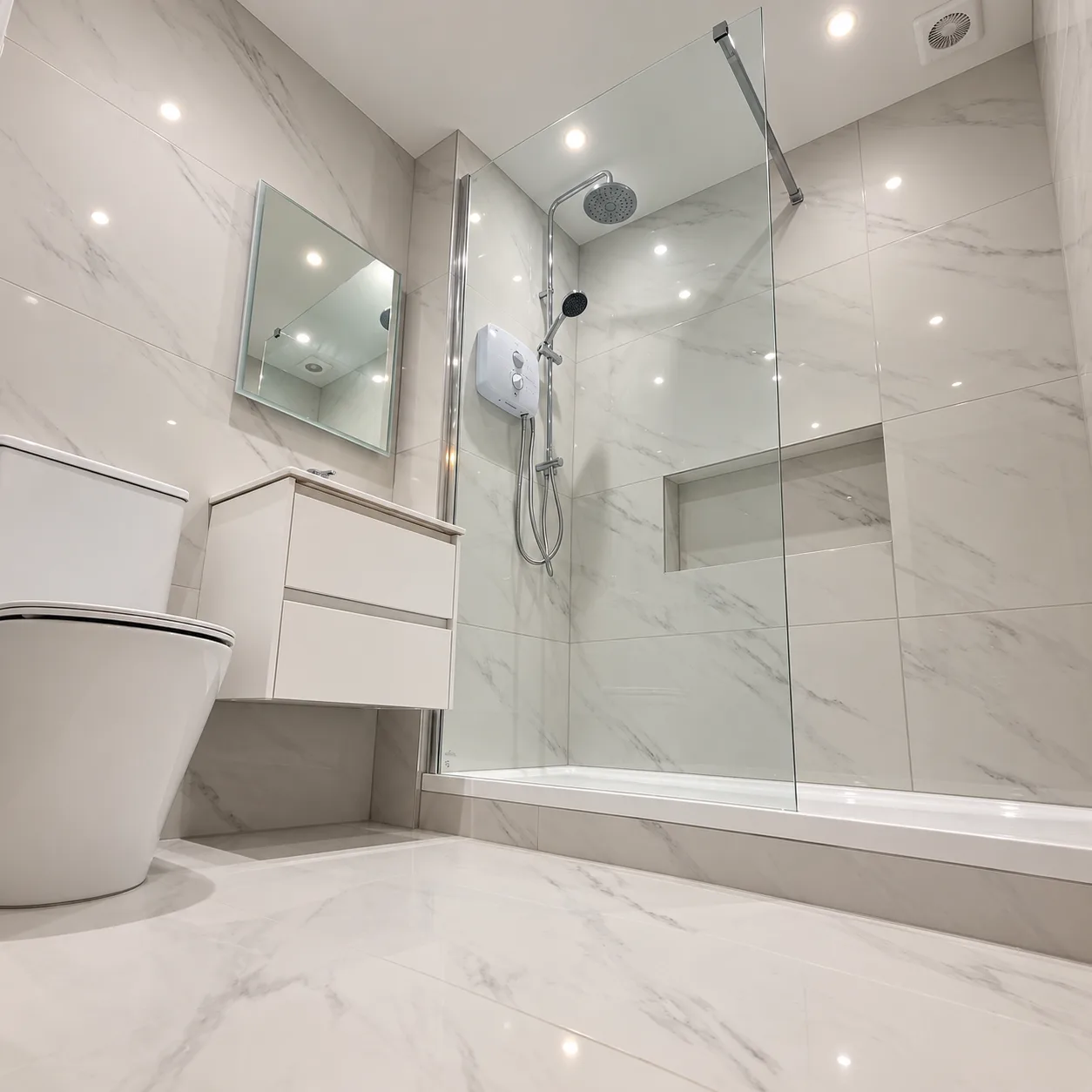 White marble-effect bathroom with walk-in shower behind a glass panel, electric shower, rain head, recessed niche, wall-hung vanity and toilet
